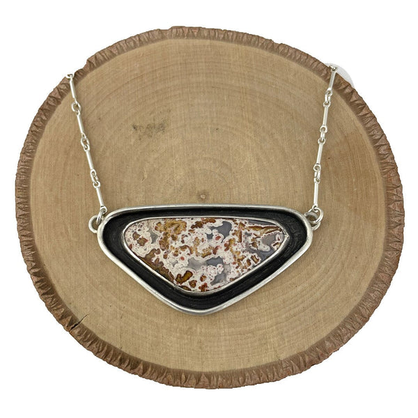 Calico Lace Agate cabochon that is set in a fine and sterling silver shadow box setting. 