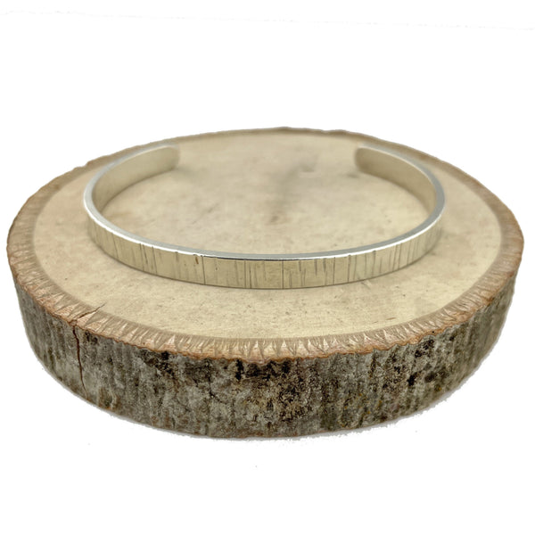 Cuff bracelet in sterling silver that has a hammered texture similar to a birch tree.